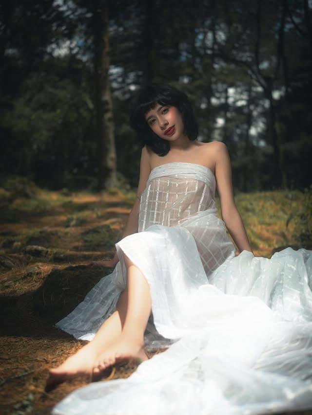 Modelo con vestido blanco translúcido en el bosque, luz cálida